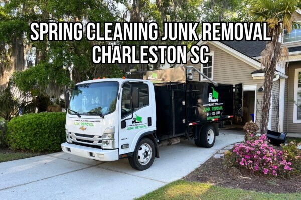 Black Dog Junk Removal truck parked in a Charleston, SC driveway during a spring cleaning junk removal service, with home exterior, landscaping, and open garage visible.
