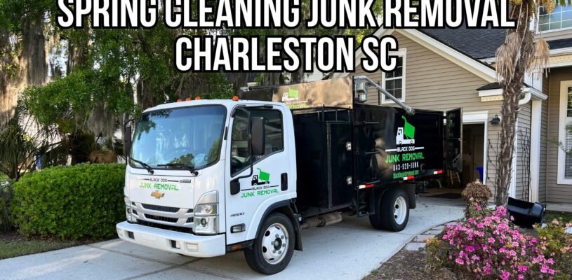 Black Dog Junk Removal truck parked in a Charleston, SC driveway during a spring cleaning junk removal service, with home exterior, landscaping, and open garage visible.