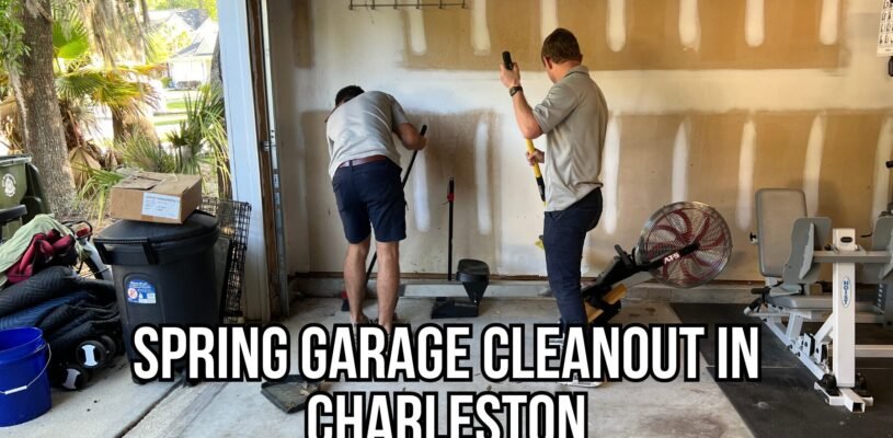 Two junk removal team members clearing out a cluttered garage in Charleston, SC during a spring cleanout, removing items like workout equipment, trash bins, and household debris.